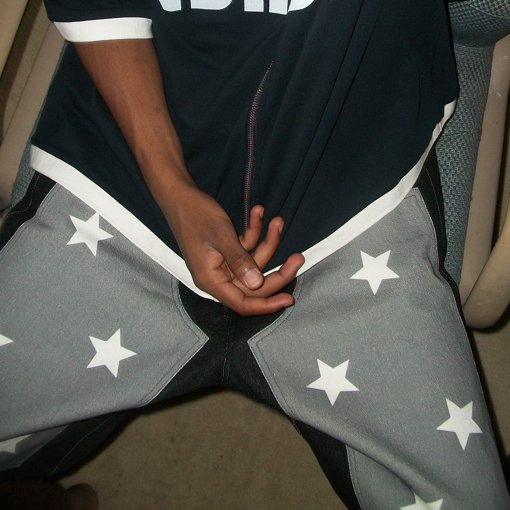 Person wearing a black outfit with white stars, sitting on a chair.